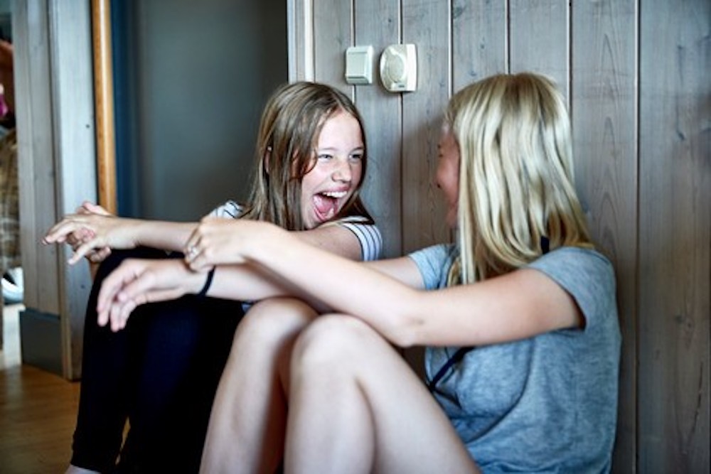 Piger sidder på gulv og griner