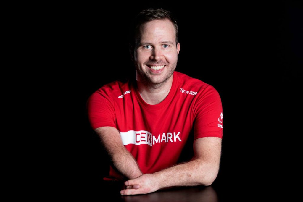 Mand i rød trøje smiler