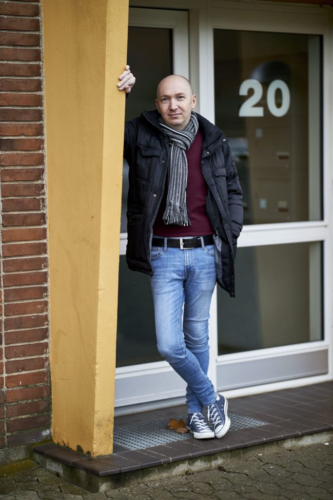 Mand læner sig op ad stolpe ved dør.